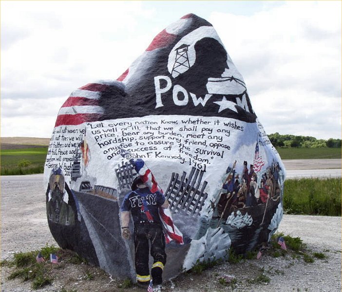 A giant rock painted with a firefighter and a fighter jet pilot also has quotes written on the rock.