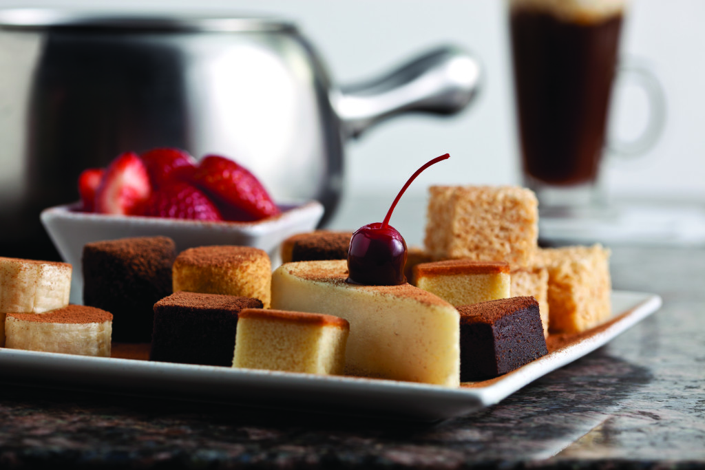 A photo of a dessert plate including strawberries, brownies, cheesecake, rice krispie treats.