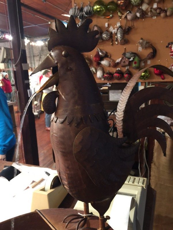 A Metal rooster(a dark brown color) for sale inside Kaffie Frederick.