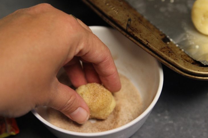 Photo of rolling the cookies in the cinnamon sugar mix.