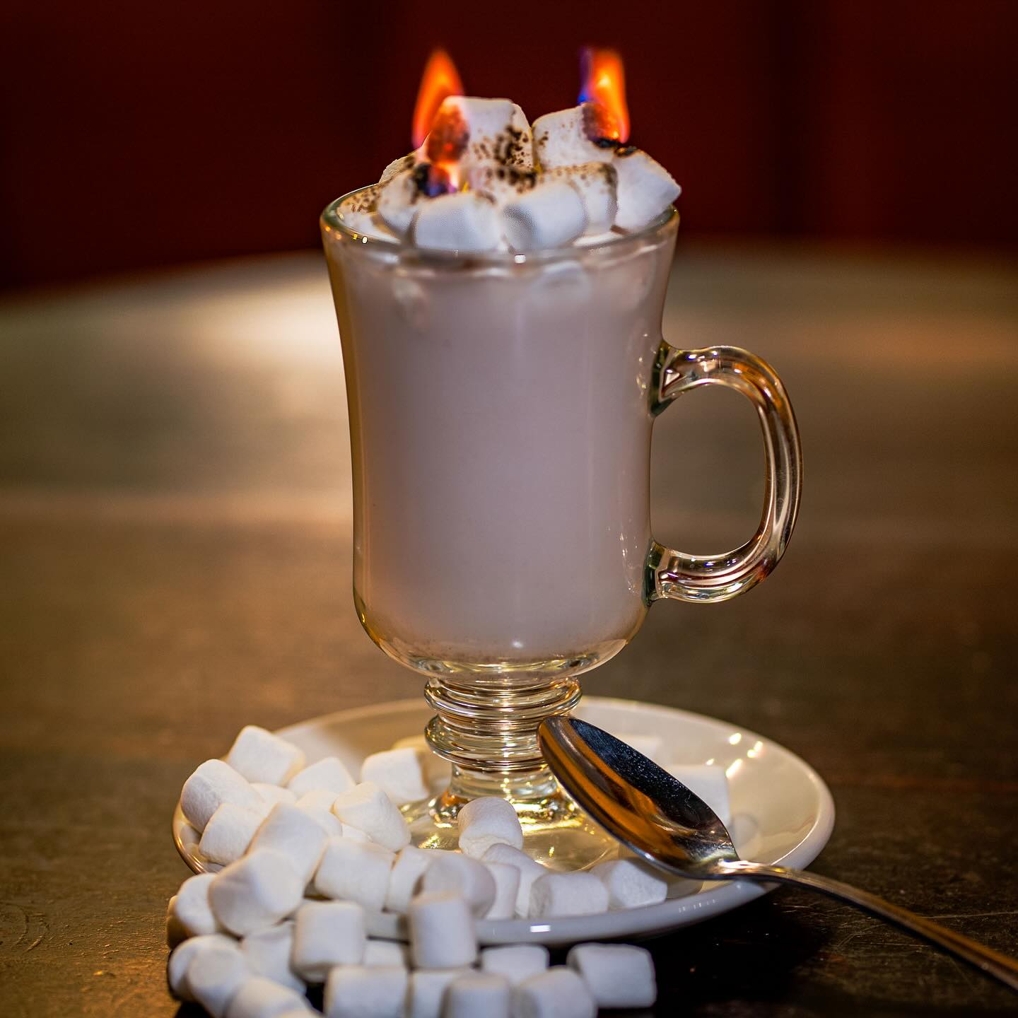 Photo of a cup of hot chocolate with marshmallows on fire on the top.