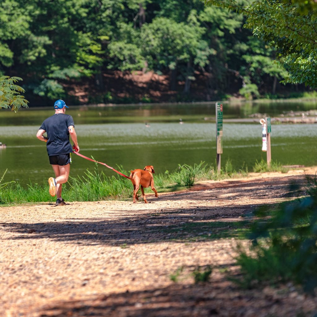 Man running with his dog along the river in a park in Brookhaven, GA