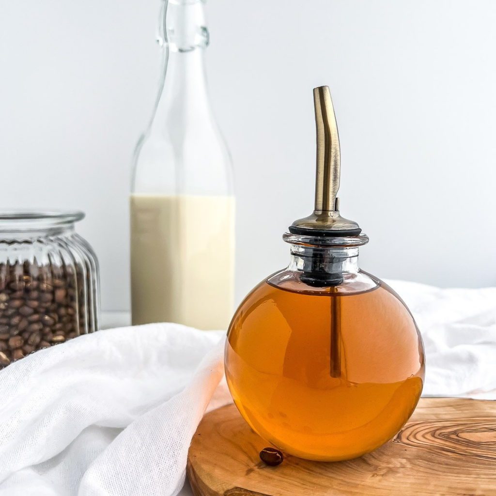 Cinnamon Dolce Syrup in a round glass jar with gold spout.