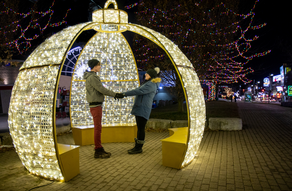 Couple standing in large lighted christmas ornament during niagara falls winter festival of lights (niagara falls tourism)