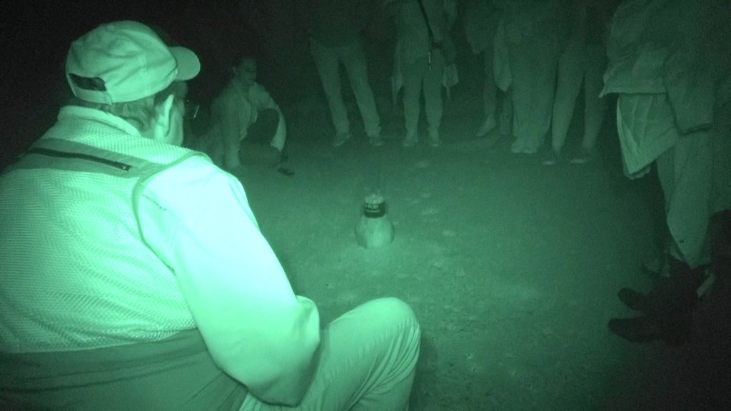 Emerald Coast Paranormal Investigators standing/sitting in circle with fliashlight in middle of circle.