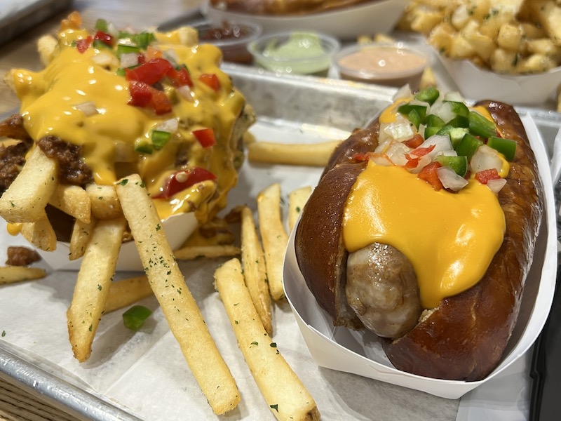 Loaded hot dog with cheese and onion with a side of loaded french fries