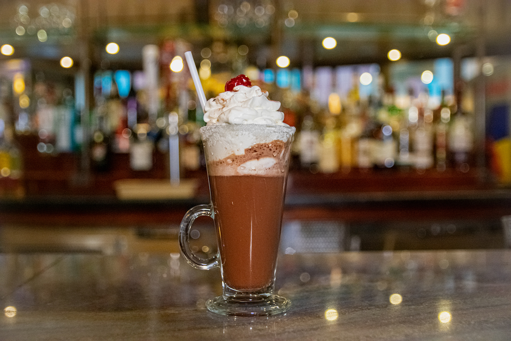 Photo of a cup hot chocolate with whipped cream and a cherry.