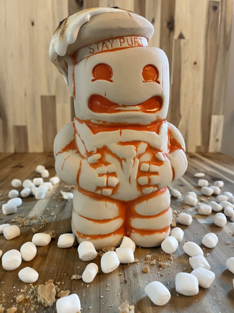 Stay Puft Christmas Cocktail recipe in a tiki mug with marshmallows scattered around.