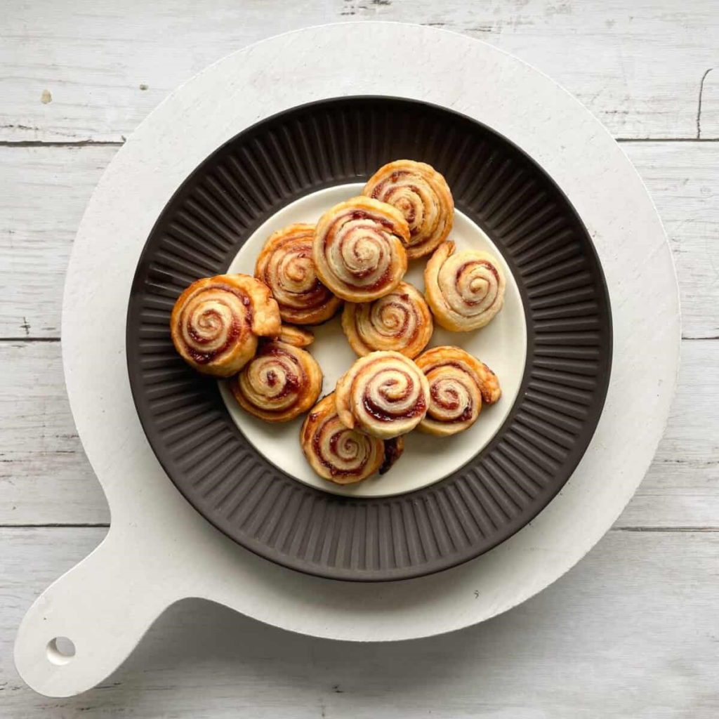 Pie Crust Cookies on a black plate with a white charger.