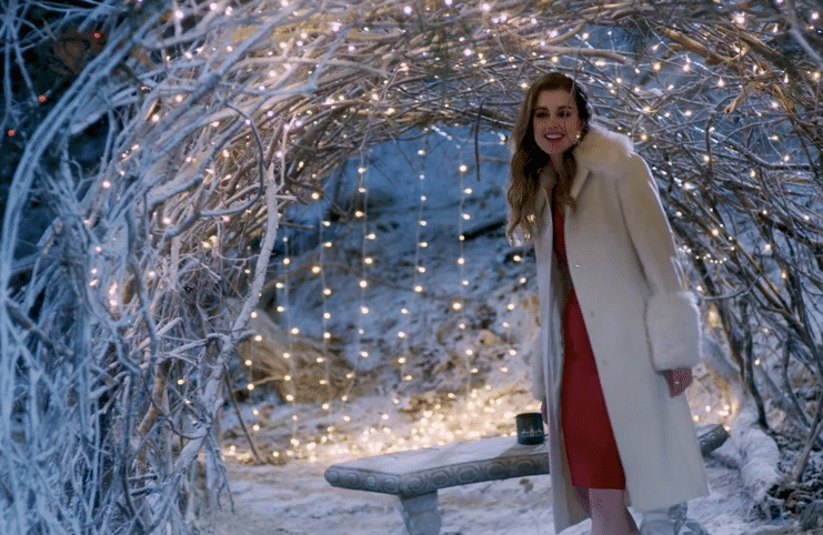 lady standing under a tunnel of lights with snow on the ground.