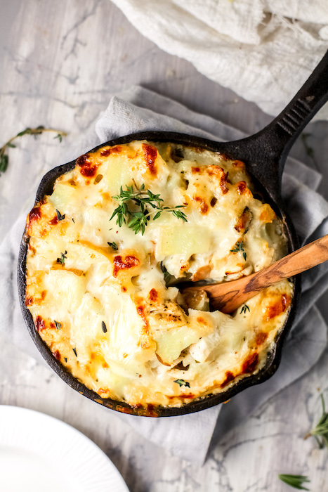 Photo of turkey potato casserole In a skillet with a wooden spoon in the dish.