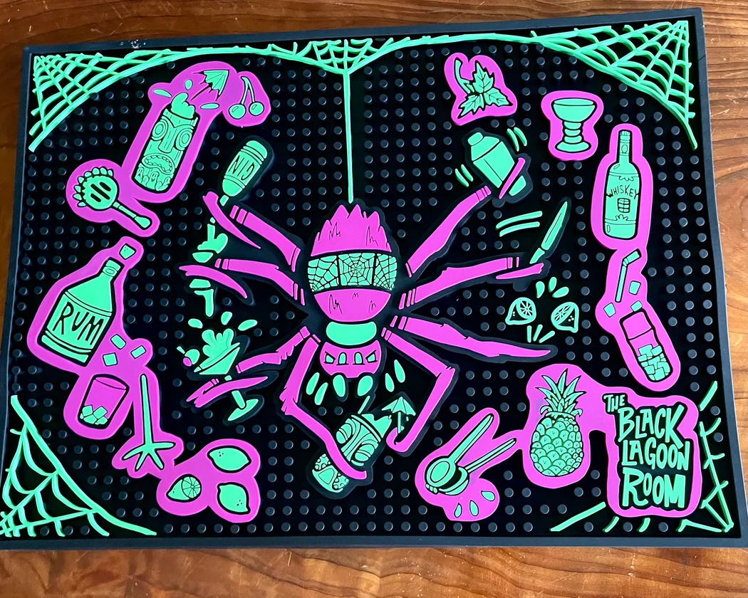Photo of a Tiki Bar Mat (purple spider and bar items) from The Black Lagoon Room.