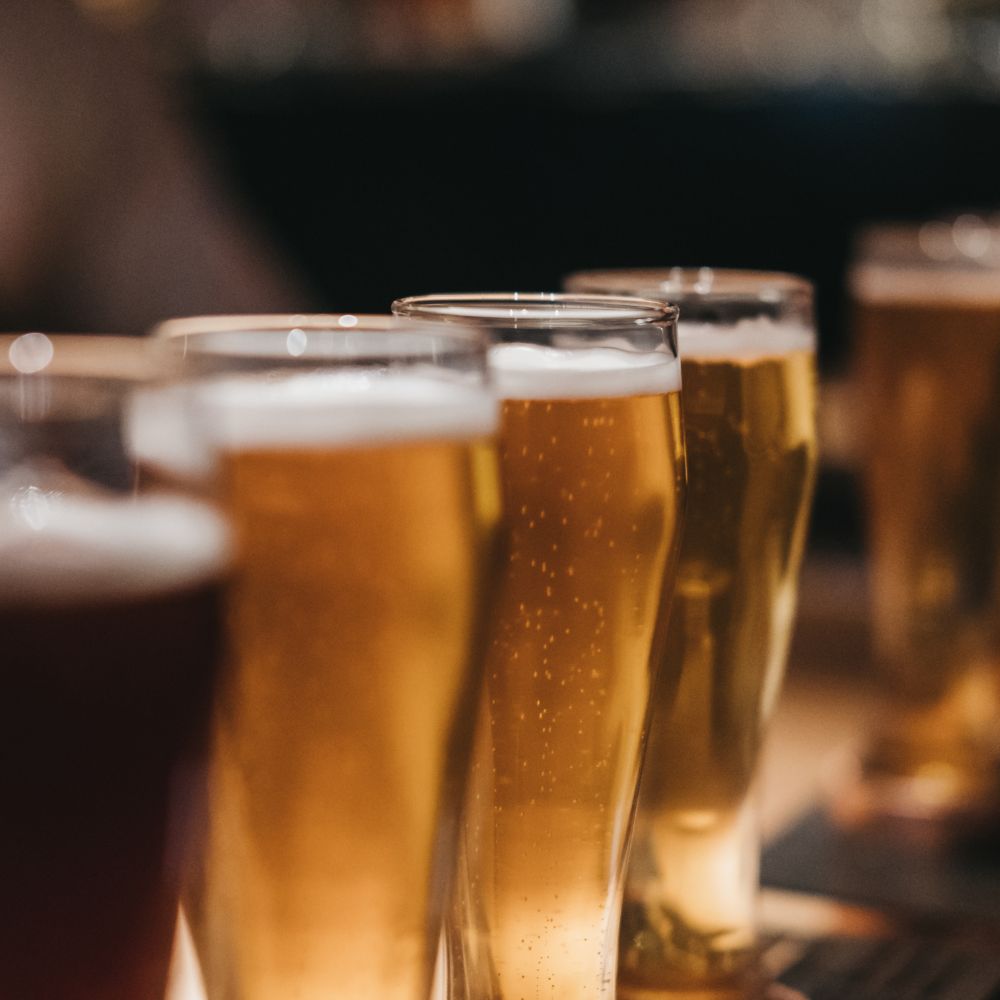 4 glass beer tumblers filled with beer ranging from dark to light.