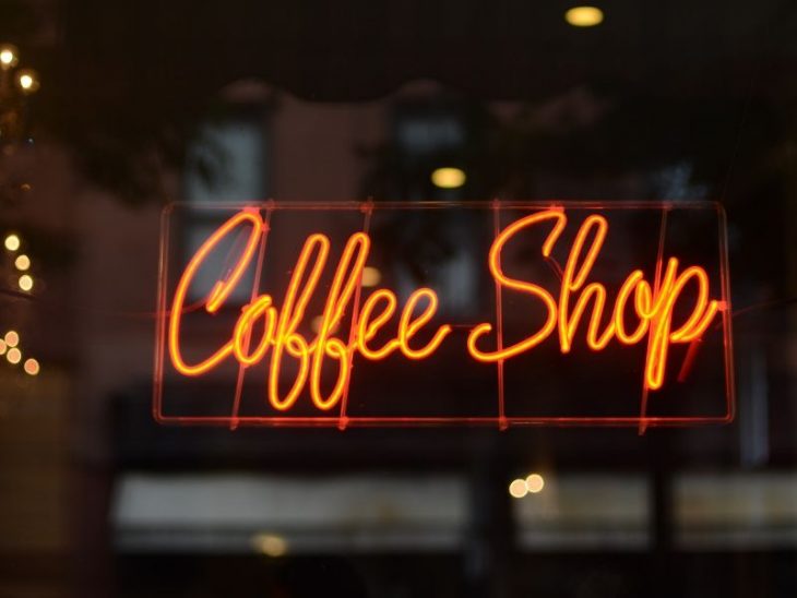 neon coffee shop sign in a script font with orange red color