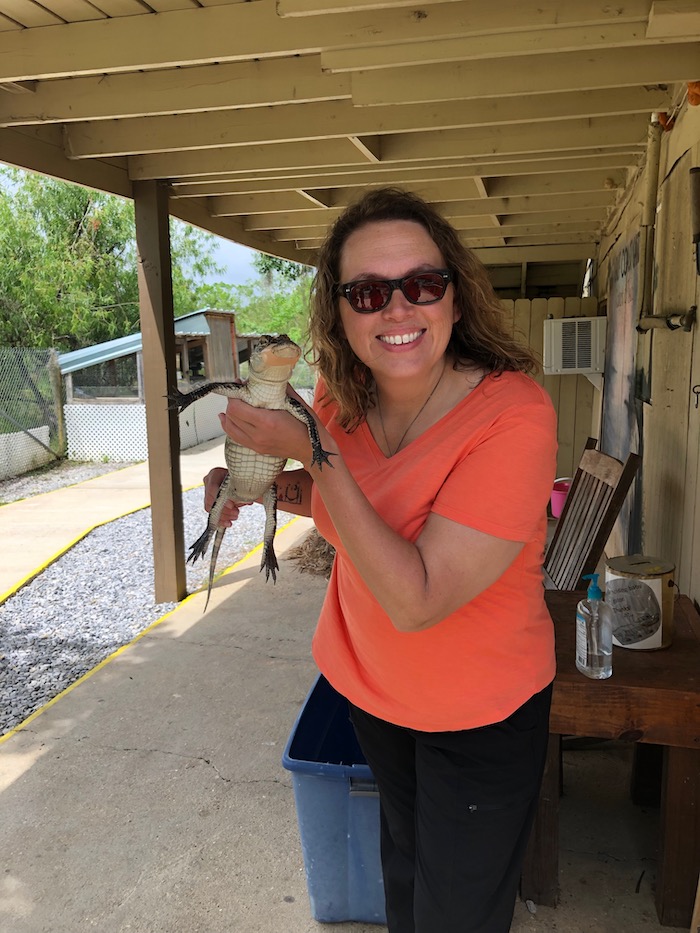 Photo of a women holding a baby alligator.