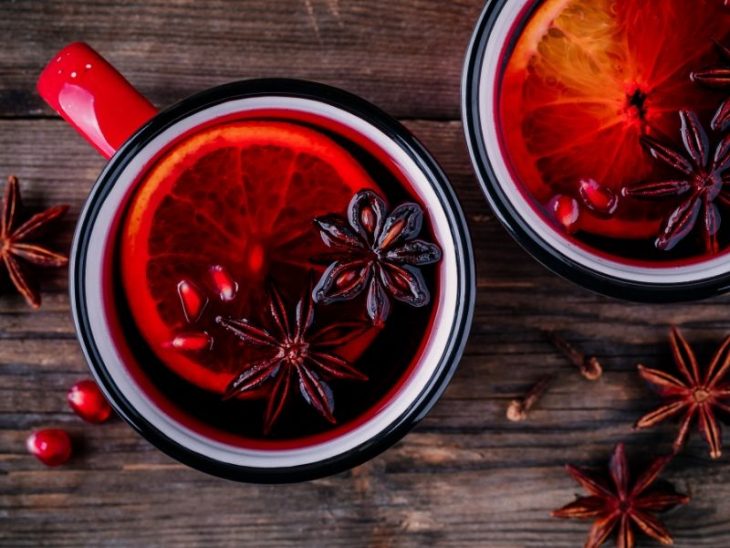 spiced apple cider photographed from above with clove and orange peel floating on top