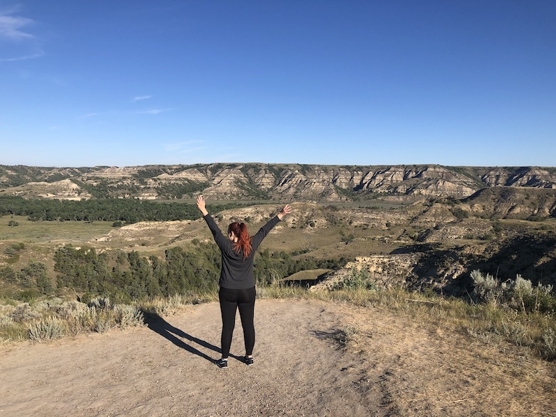 Girl with arms raised at the top of wind canyon trail